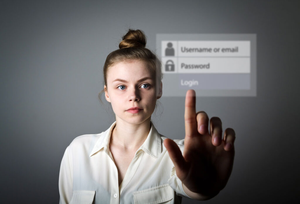A young woman reaches toward a virtual login screen—reminding us how everyday logins can be the weak link hackers exploit if passwords aren’t strong or unique.